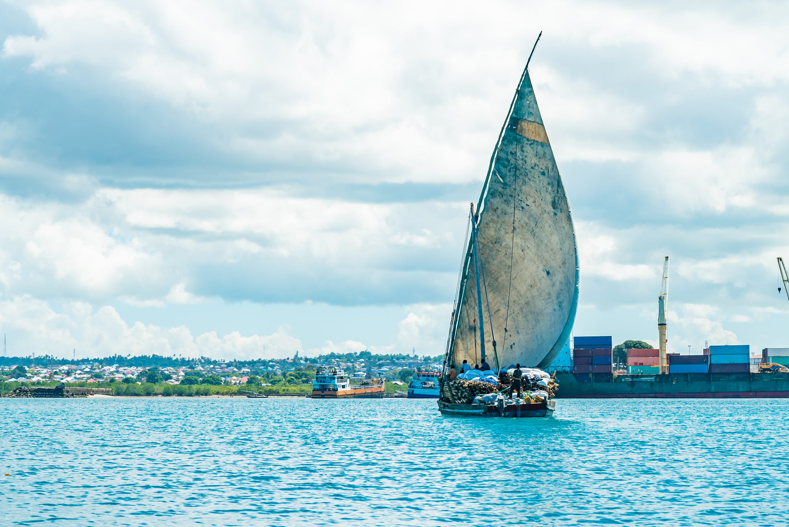 Wooden ship with timber in water of Indian ocean heading port of Stone Town. Zanzibar, Tanzania.